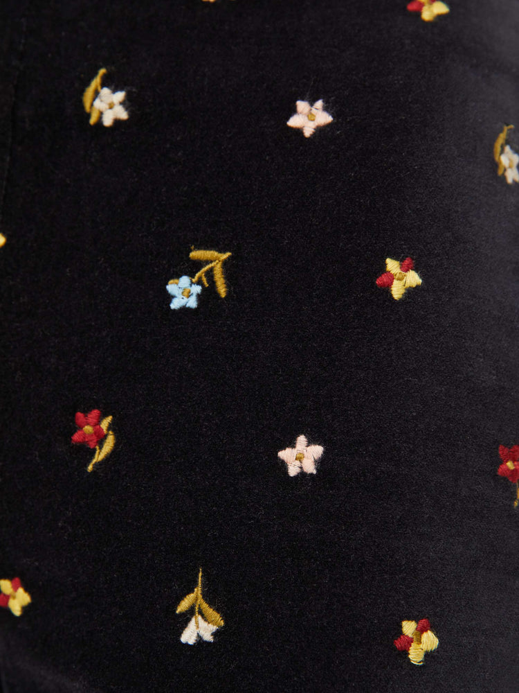 Swatch view of a woman in black with colorful floral details pants with a mid rise and a wide flared leg.