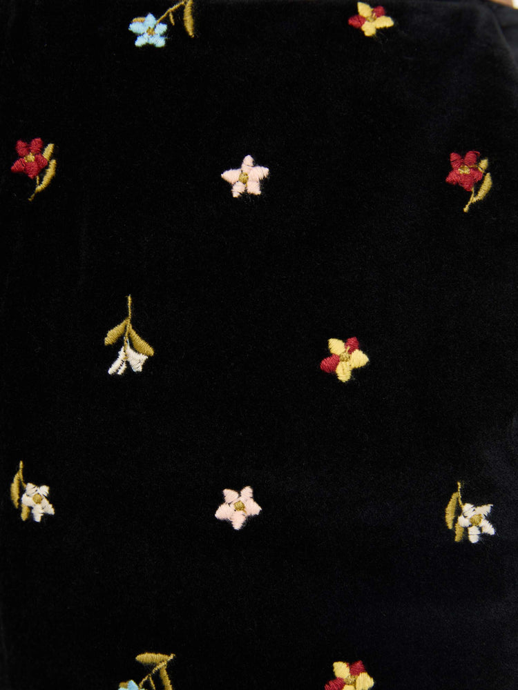 Swatch view of a woman in black with colorful floral details pants with a mid rise and a wide flared leg.