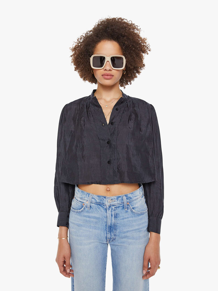 Front view of a woman in a black shirt with a collared V-neck, long balloon sleeves and a cropped fit.