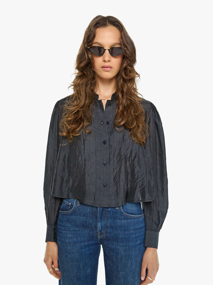 Front view of a woman in a black shirt with a collared V-neck, long balloon sleeves and a cropped fit.