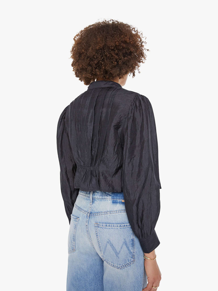 Back view of a woman in a black shirt with a collared V-neck, long balloon sleeves and a cropped fit.