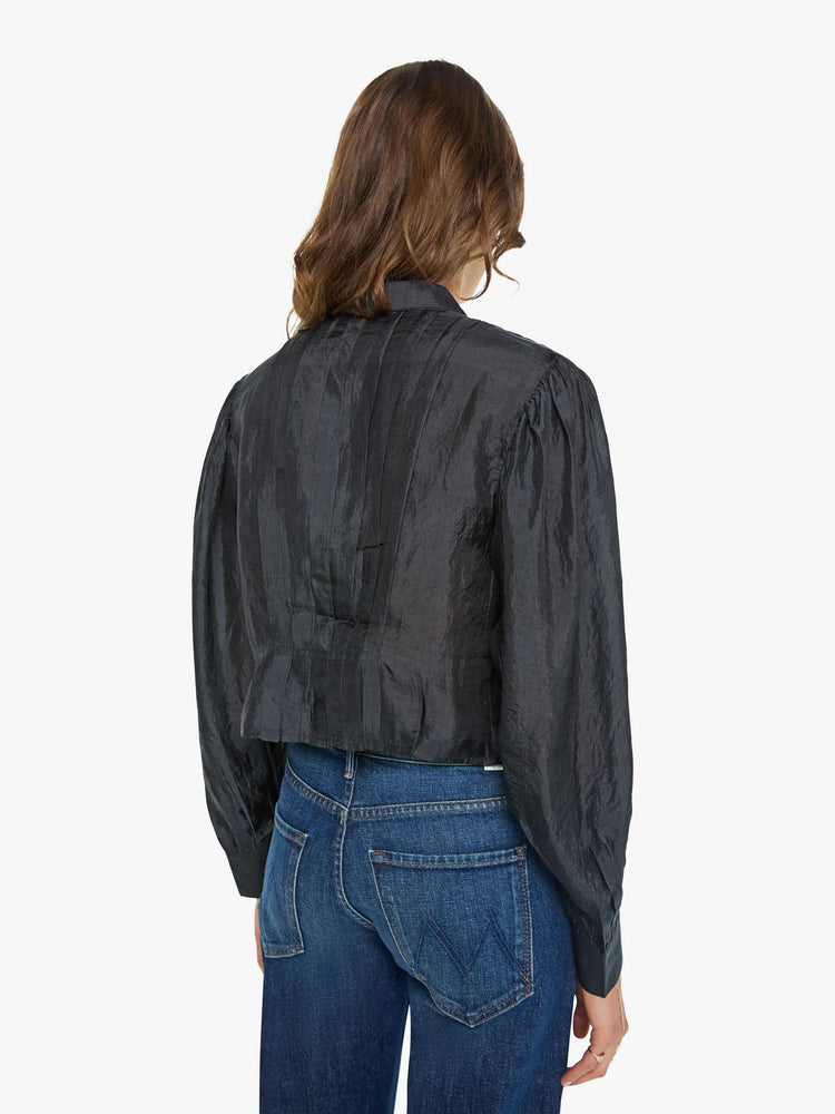 Back view of a woman in a black shirt with a collared V-neck, long balloon sleeves and a cropped fit.