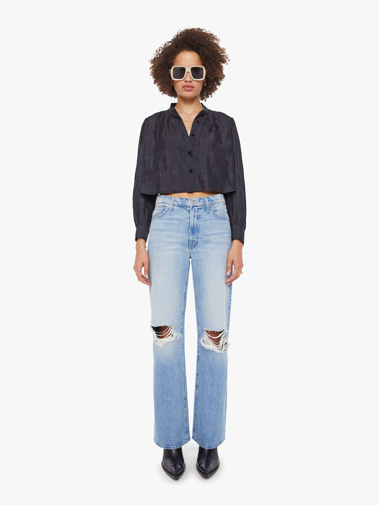 Full body view of a woman in a black shirt with a collared V-neck, long balloon sleeves and a cropped fit.