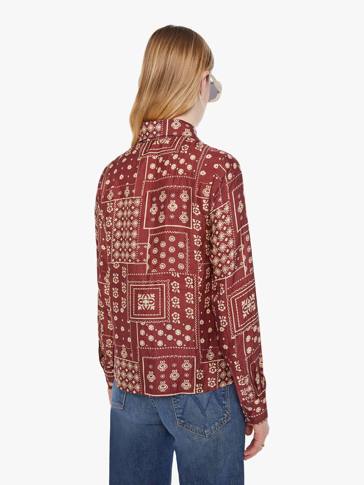 Back  view of a woman in a brown with a cream paisley print shirt with a collared neck, long sleeves and buttons down the front.
