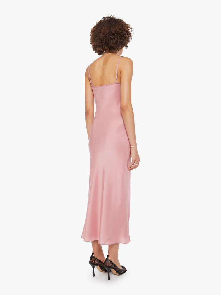 Back view of a woman  in pink dress with thin spaghetti straps, a curved neck, narrow fit and a flowy ankle-length hem.