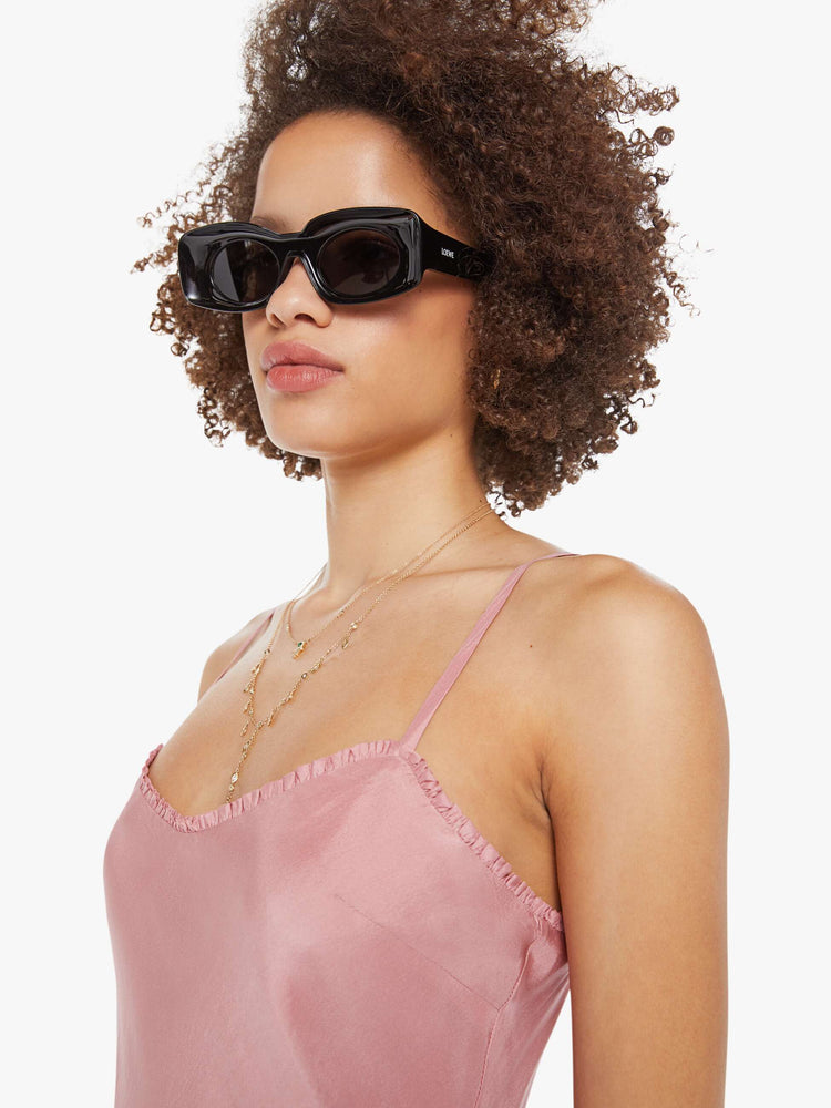 Close up view of a woman  in pink dress with thin spaghetti straps, a curved neck, narrow fit and a flowy ankle-length hem.