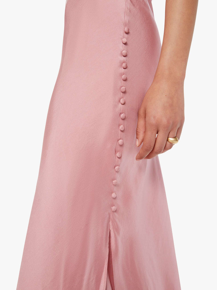 Close up view of a woman  in pink dress with thin spaghetti straps, a curved neck, narrow fit and a flowy ankle-length hem.