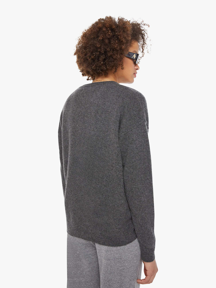 Back view of a woman in a sweater  cashmere in dark grey, the sweater has a crewneck, drop shoulders and a loose, comfortable fit.