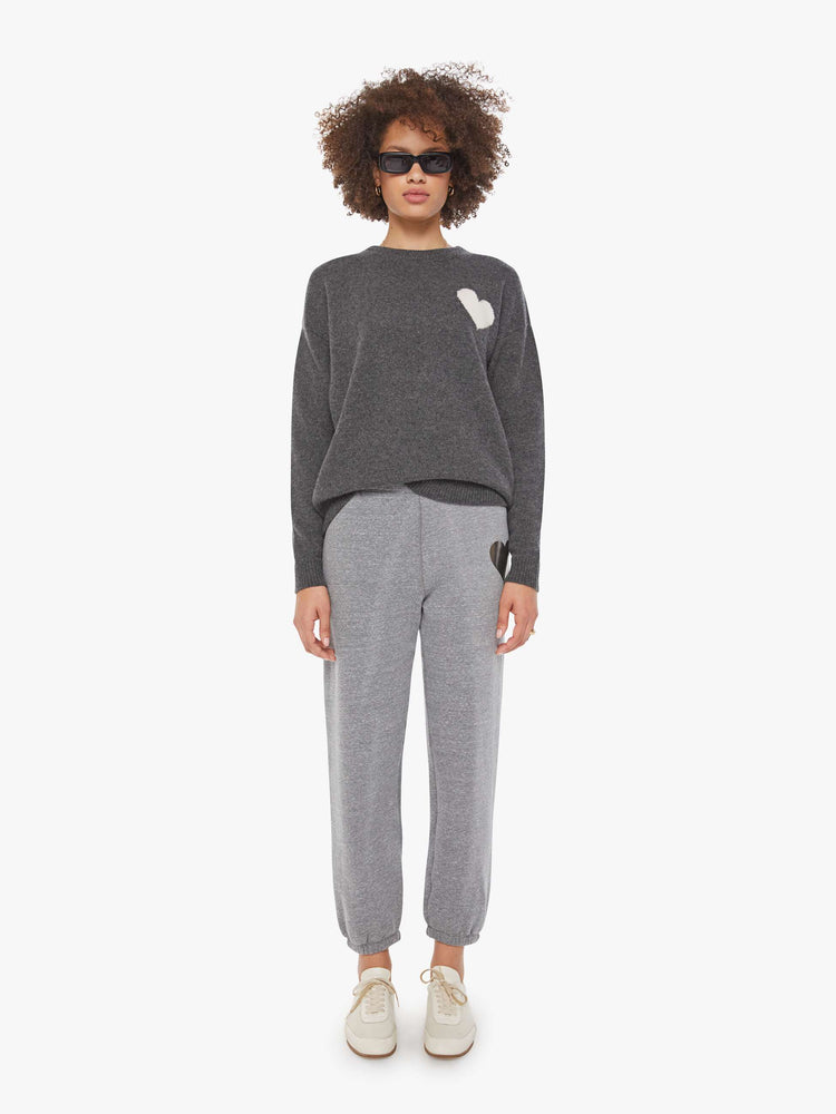 Full body view of a woman in a sweater  cashmere in dark grey, the sweater has a crewneck, drop shoulders and a loose, comfortable fit.