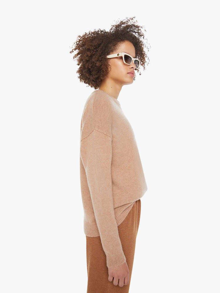 Side view of a woman in a light khaki sweater with a crewneck and drop shoulders.