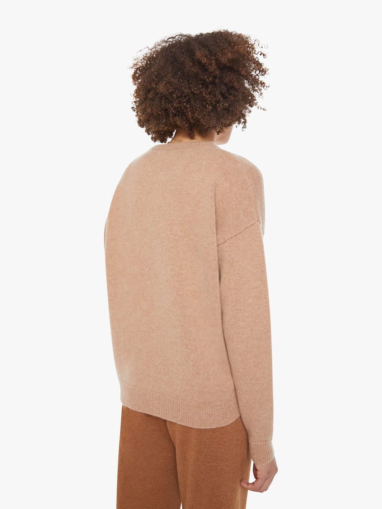 Back view of a woman in a light khaki sweater with a crewneck and drop shoulders.