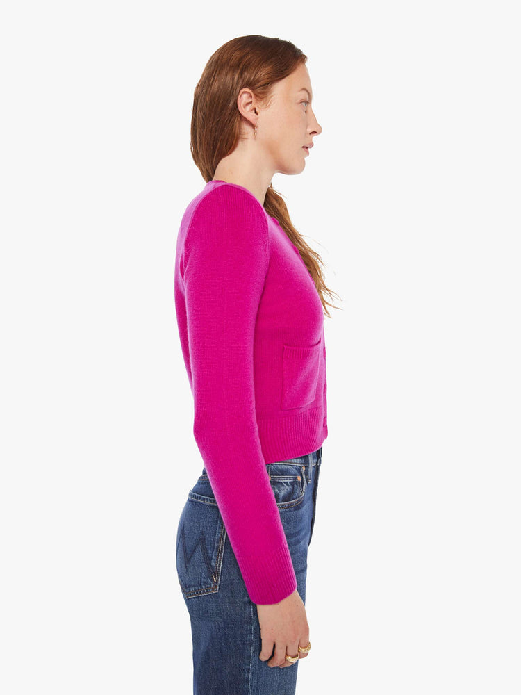 Side view of a woman in a magenta cardigan with tonal buttons down the front.