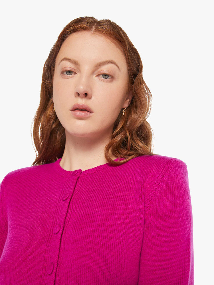 Close up view of a woman in a magenta cardigan with tonal buttons down the front.