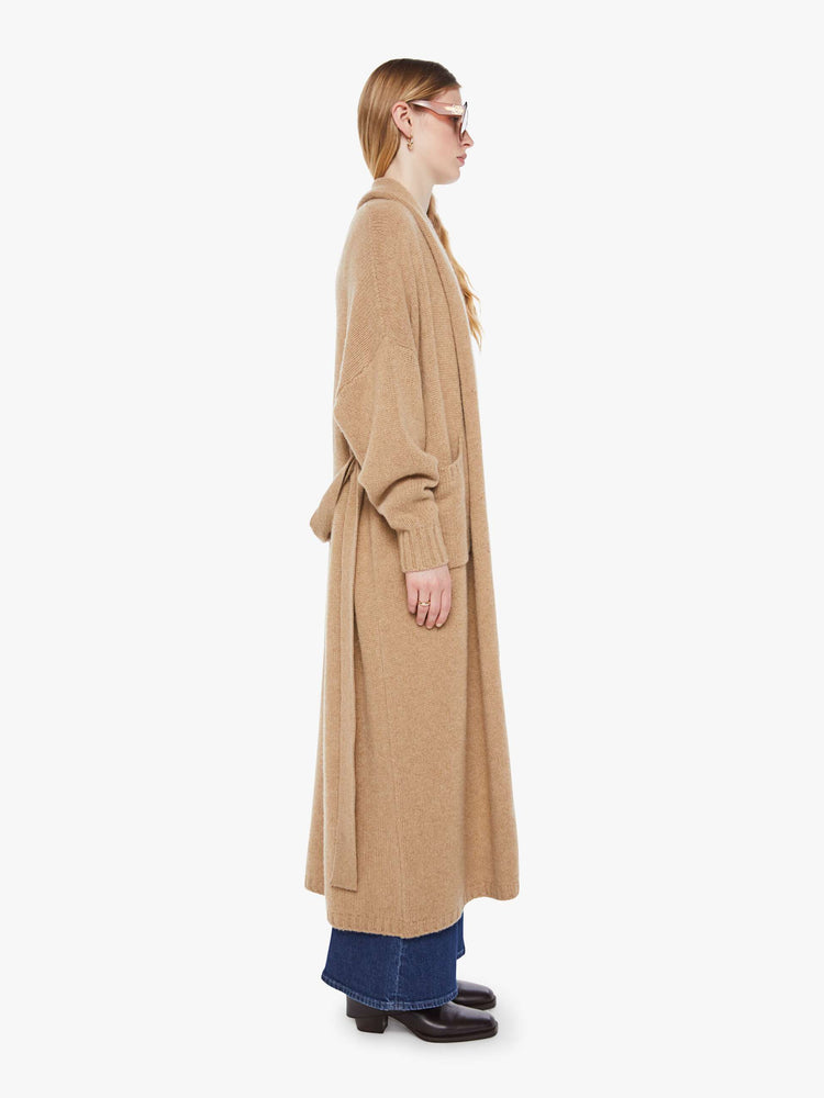 Side view of woman in a light khaki  knit duster with a shawl collar, optional tie belt and ankle-length hem. 
