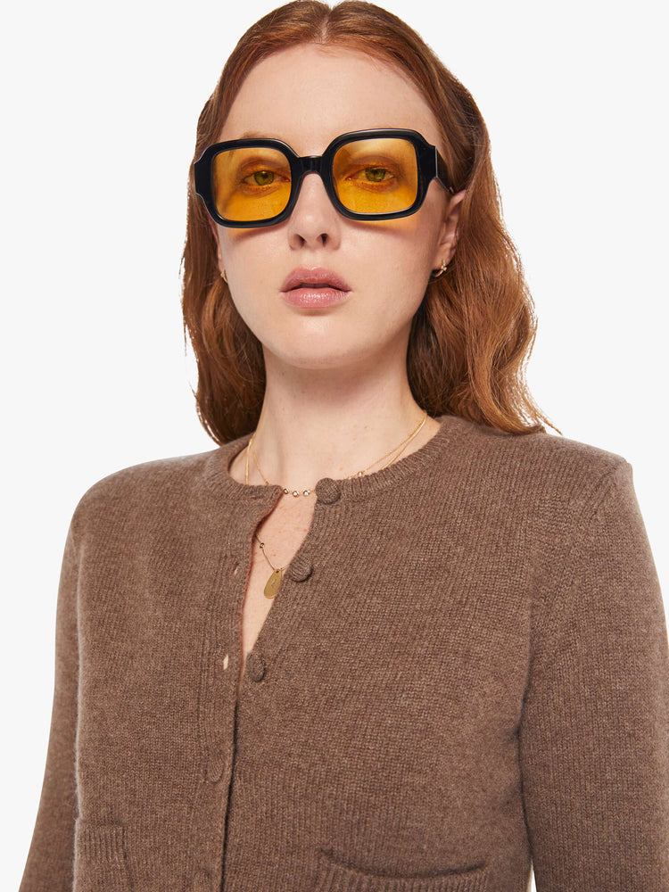 Close up view of a woman in a cashmere chocolate brown cardigan with tonal buttons down the front.