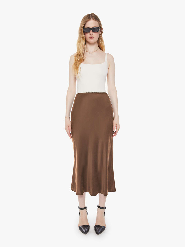 Front view of a woman in a chocolate brown bias cut skirt with a straight fit and a flowy calf-grazing hem.