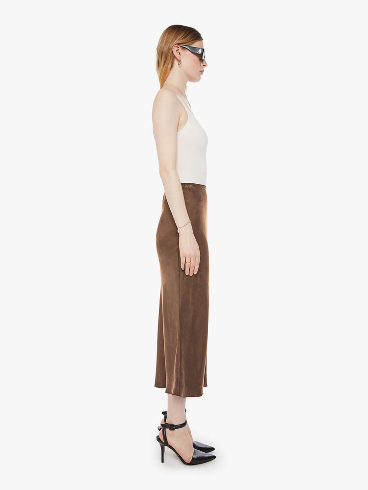 Side view of a woman in a chocolate brown bias cut skirt with a straight fit and a flowy calf-grazing hem.