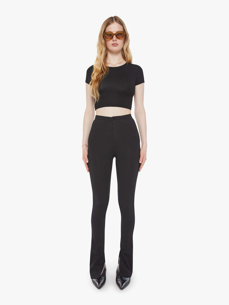 Front view of a woman in a black high rise pant and an extra-long inseam with a split hem.
