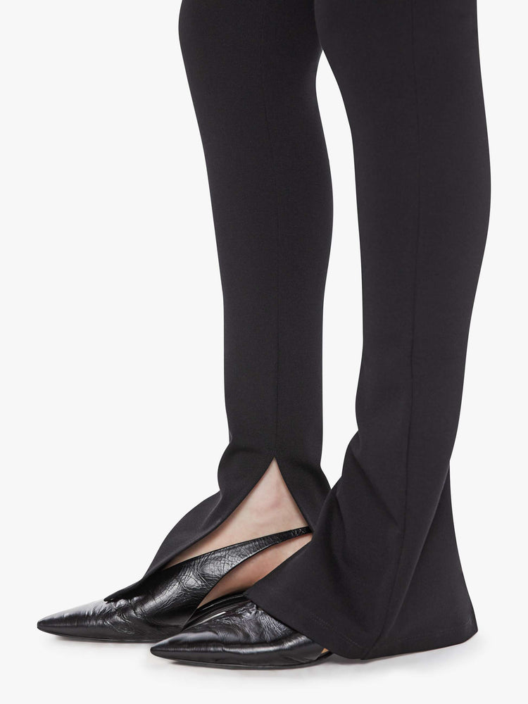 Hem  view of a woman in a black high rise pant and an extra-long inseam with a split hem.