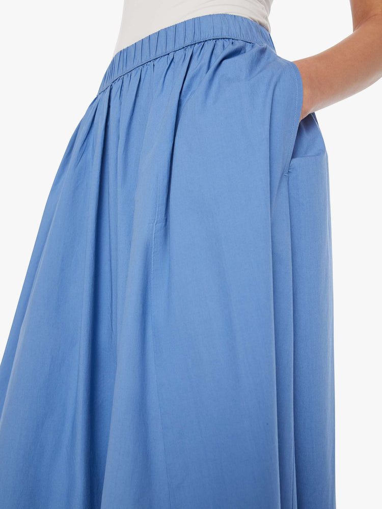 Close up view of a woman in a blue skirt with  a high rise, ruffled waistband and flowy fit.