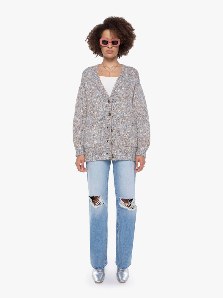 Front view of a woman in a  grey, baby blue and white mélange, the cardigan has a deep V-neck, drop shoulders, buttons down the front and thick ribbed hems.