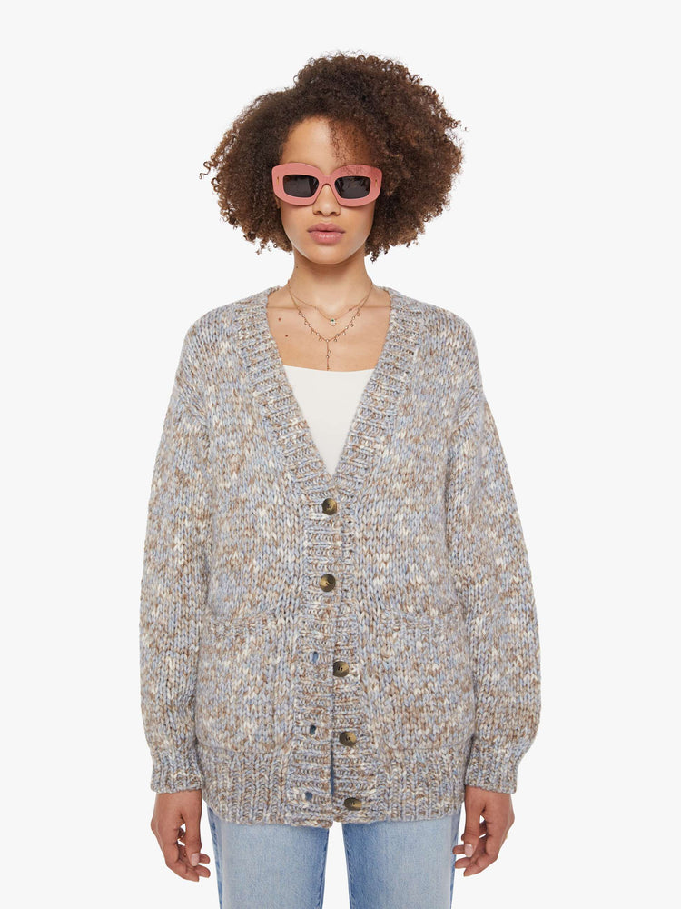 Front view of a woman in a  grey, baby blue and white mélange, the cardigan has a deep V-neck, drop shoulders, buttons down the front and thick ribbed hems.