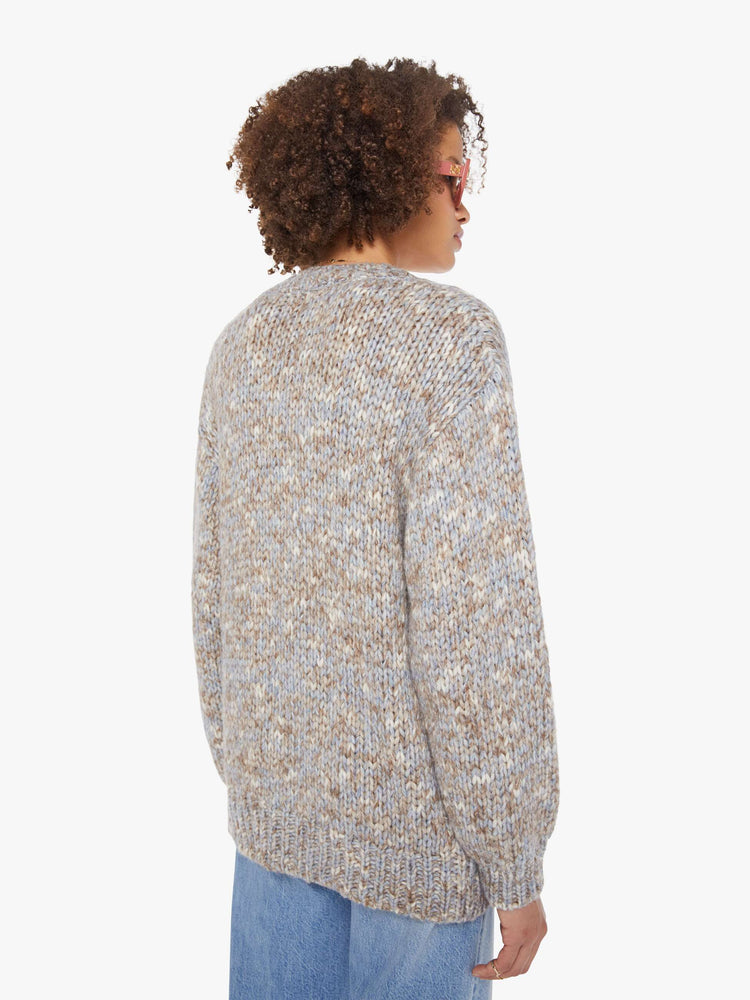 Back view of a woman in a  grey, baby blue and white mélange, the cardigan has a deep V-neck, drop shoulders, buttons down the front and thick ribbed hems.