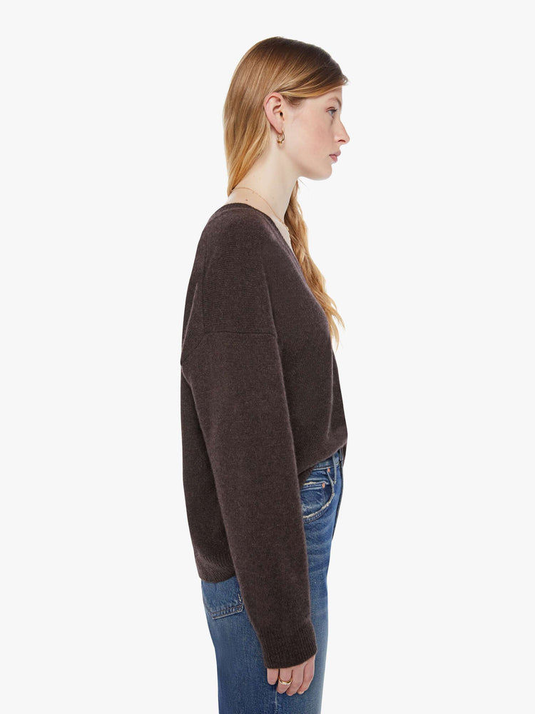 Side view of a woman in a rich brown sweater is designed with a deep V-neck, drop shoulders, long sleeves and a slightly oversized fit.