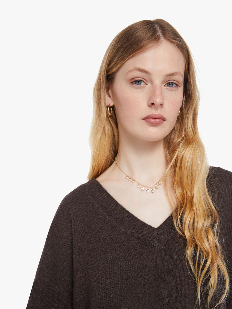 Close up view of a woman in a rich brown sweater is designed with a deep V-neck, drop shoulders, long sleeves and a slightly oversized fit.
