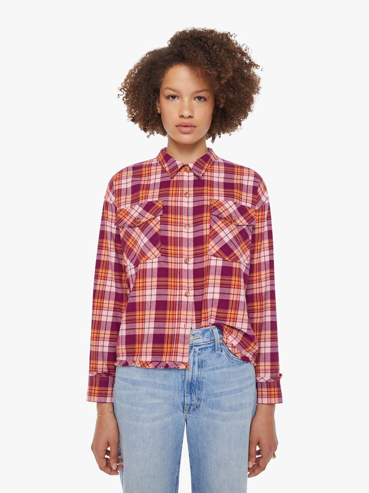 Front view of a woman in an orange and hot pink plaid long-sleeve shirt with patch pockets, drop shoulders and a slightly cropped fit.