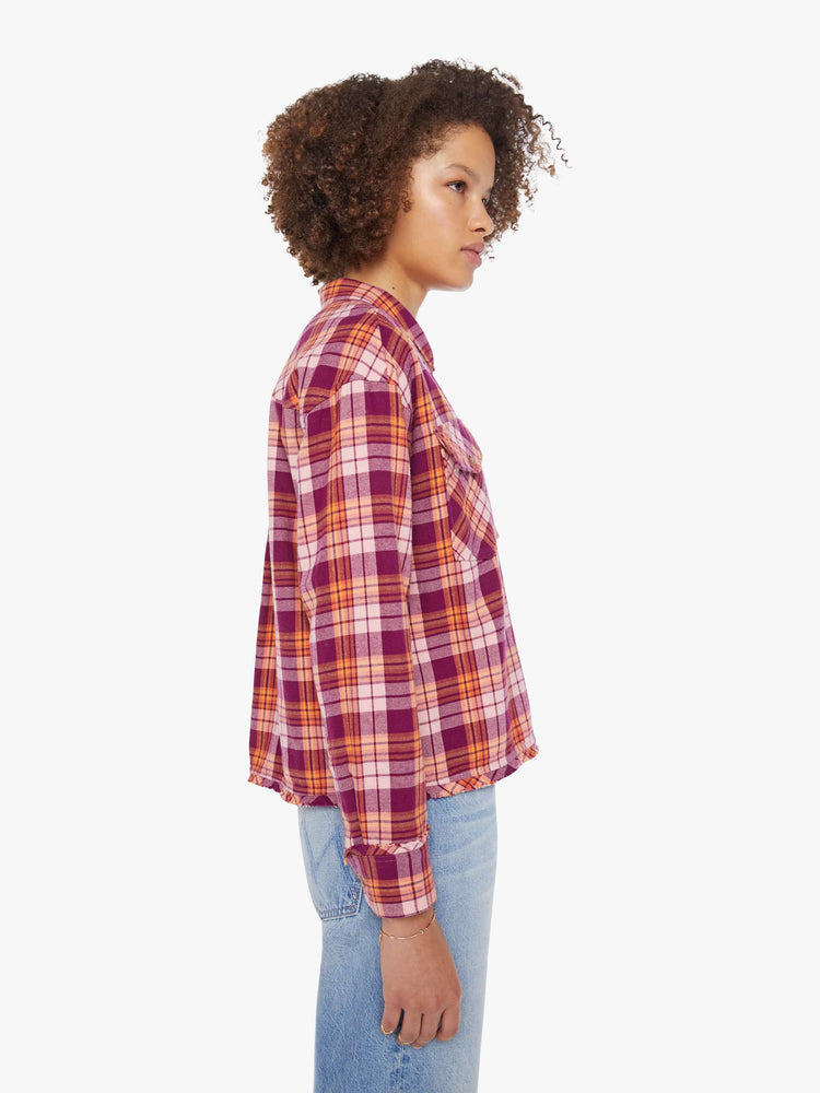 Side view of a woman in an orange and hot pink plaid long-sleeve shirt with patch pockets, drop shoulders and a slightly cropped fit.
