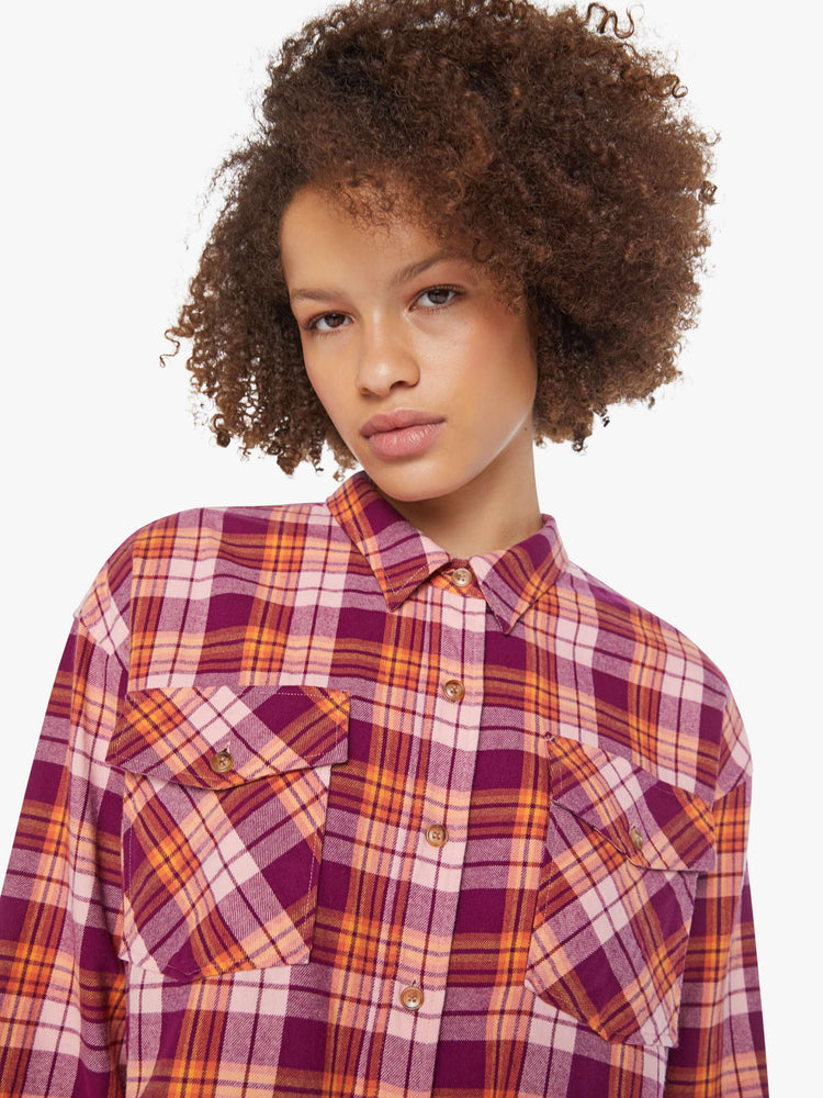 Close up view of a woman in an orange and hot pink plaid long-sleeve shirt with patch pockets, drop shoulders and a slightly cropped fit.