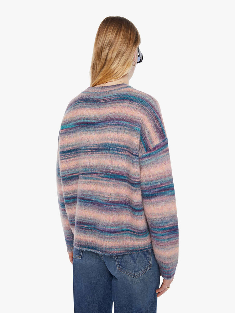 Back view of a woman in a pink and blue stripes the long-sleeve sweater with drop shoulders and an oversized fit.