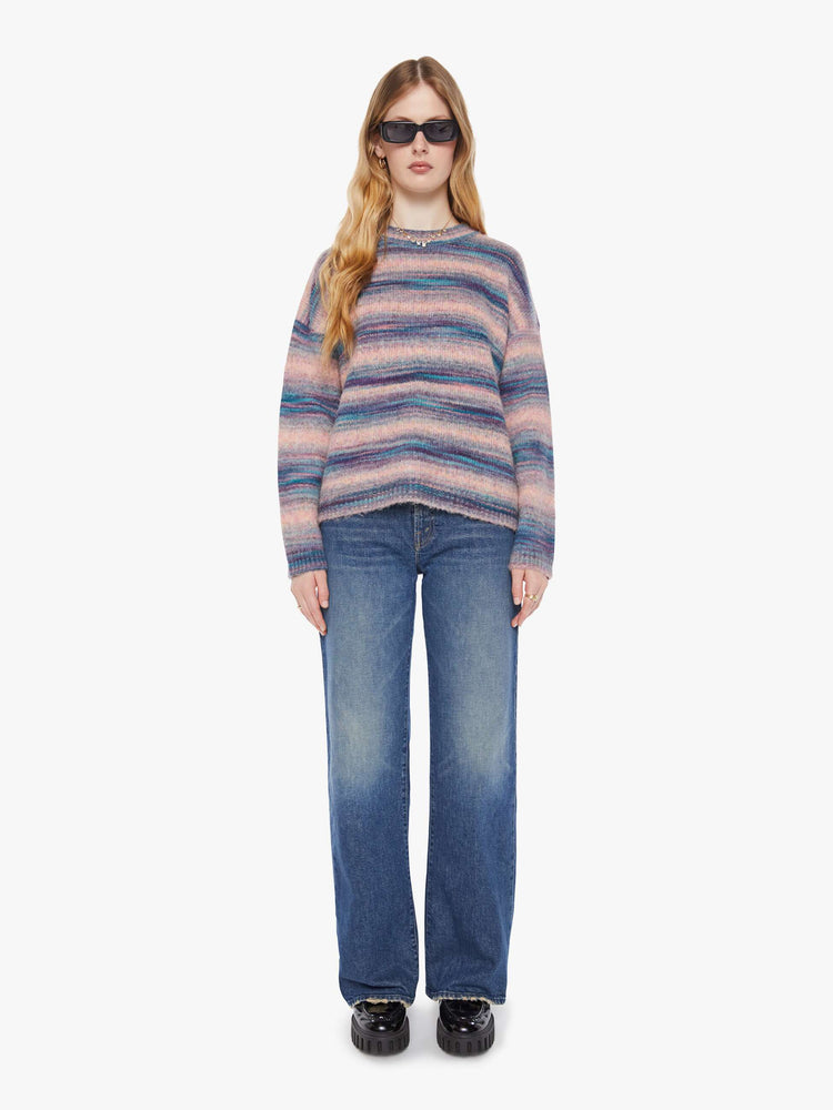 Full body view of a woman in a pink and blue stripes the long-sleeve sweater with drop shoulders and an oversized fit.