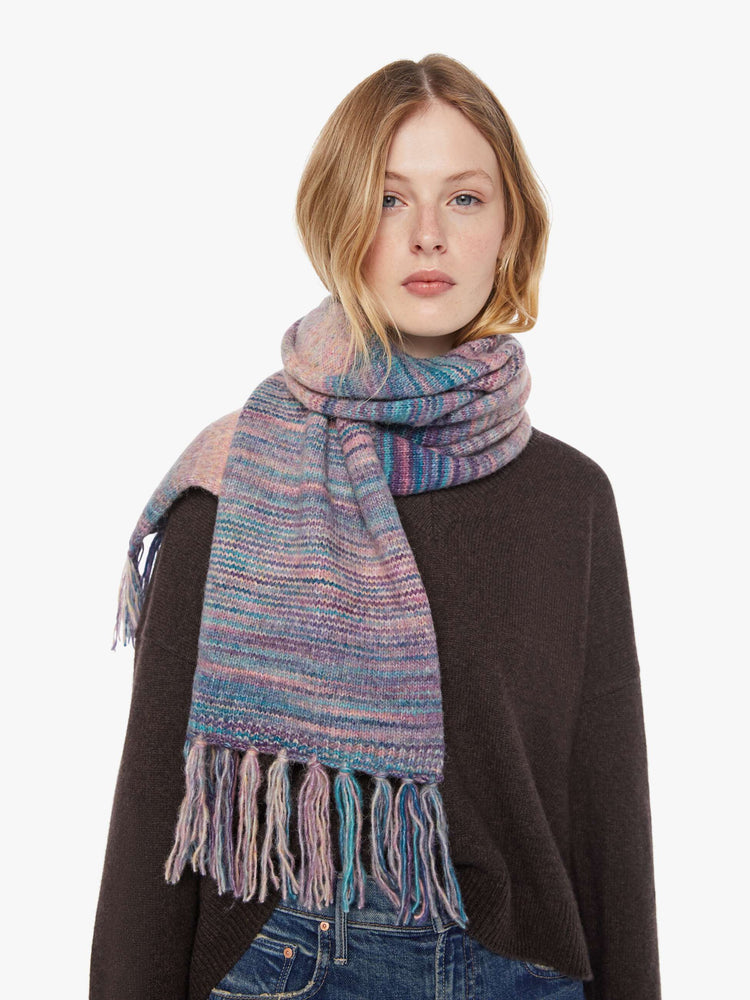 Front view of a woman in a pink and blue stripes scarf with an extra-wide design and tasseled hem.
