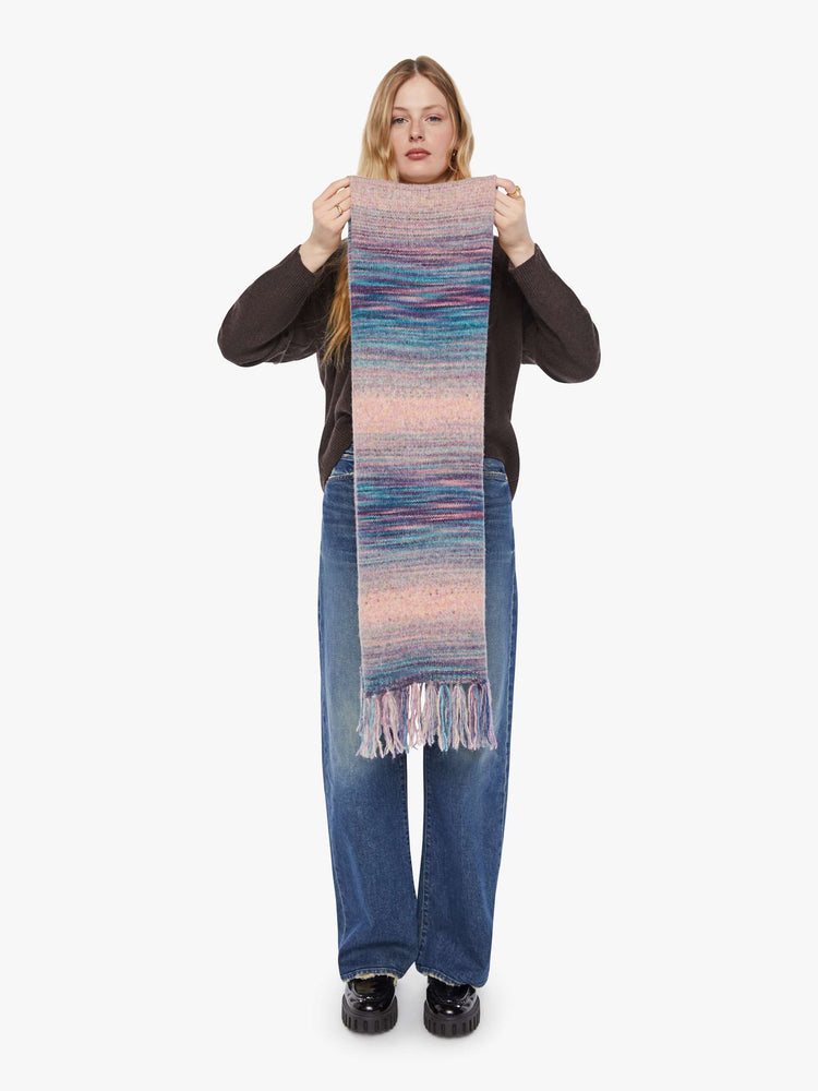 Full view of a woman in a pink and blue stripes scarf with an extra-wide design and tasseled hem.