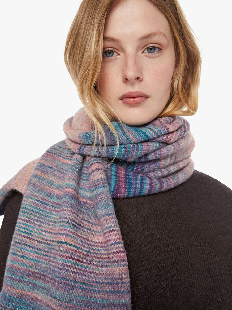 Close up view of a woman in a pink and blue stripes scarf with an extra-wide design and tasseled hem.