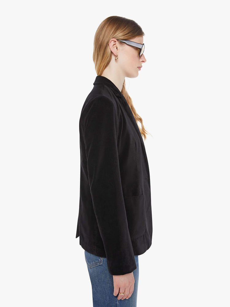 Side view of a woman in a black blazer is designed with a notched collar, deep V-neck, single-button closure and a slightly boxy fit.