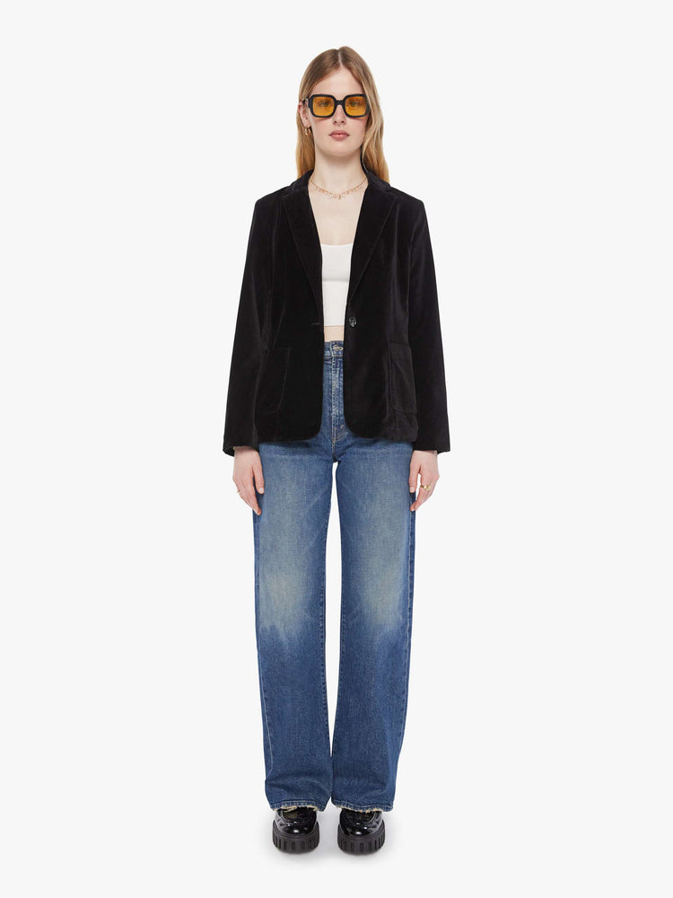 Full body view of a woman in a black blazer is designed with a notched collar, deep V-neck, single-button closure and a slightly boxy fit.