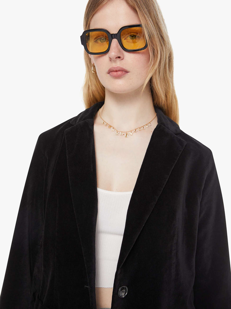 Close up view of a woman in a black blazer is designed with a notched collar, deep V-neck, single-button closure and a slightly boxy fit.