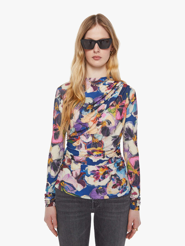 Front view of a woman in an abstract flower top with a crewneck that drapes across the chest and gathered side seams for a ruched look.
