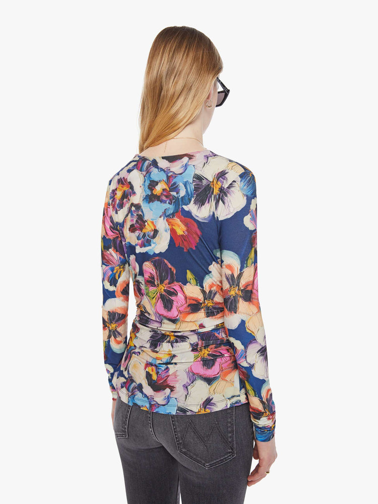 Back view of a woman in an abstract flower top with a crewneck that drapes across the chest and gathered side seams for a ruched look.