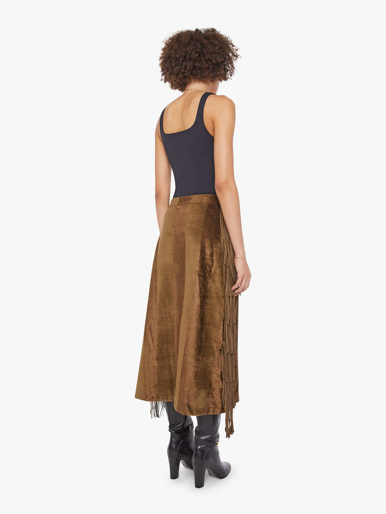 Back view of a woman in a sage skirt with a high rise, fringe down the sides and a loose, flowy fit. 