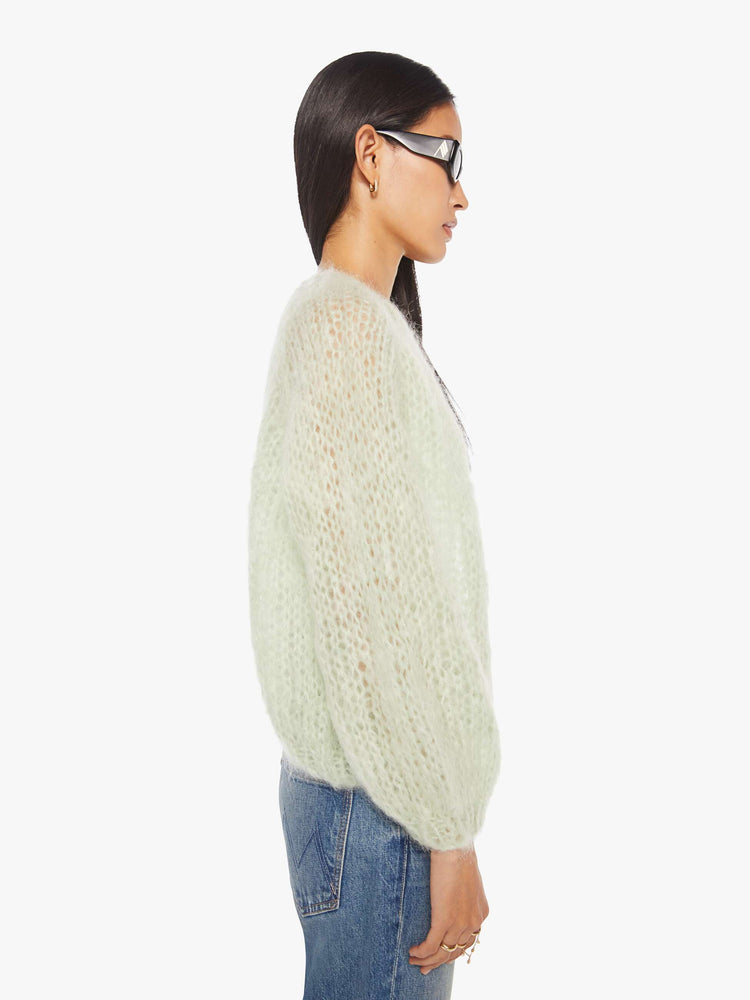 Side view of a woman in a mint green cardigan.