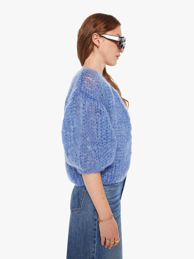 Side view of a woman in a baby blue bomber jacket inspired cardigan.