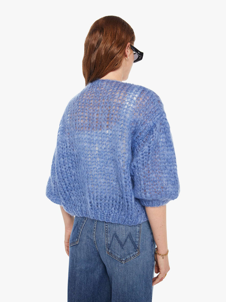 Back view of a woman in a baby blue bomber jacket inspired cardigan.