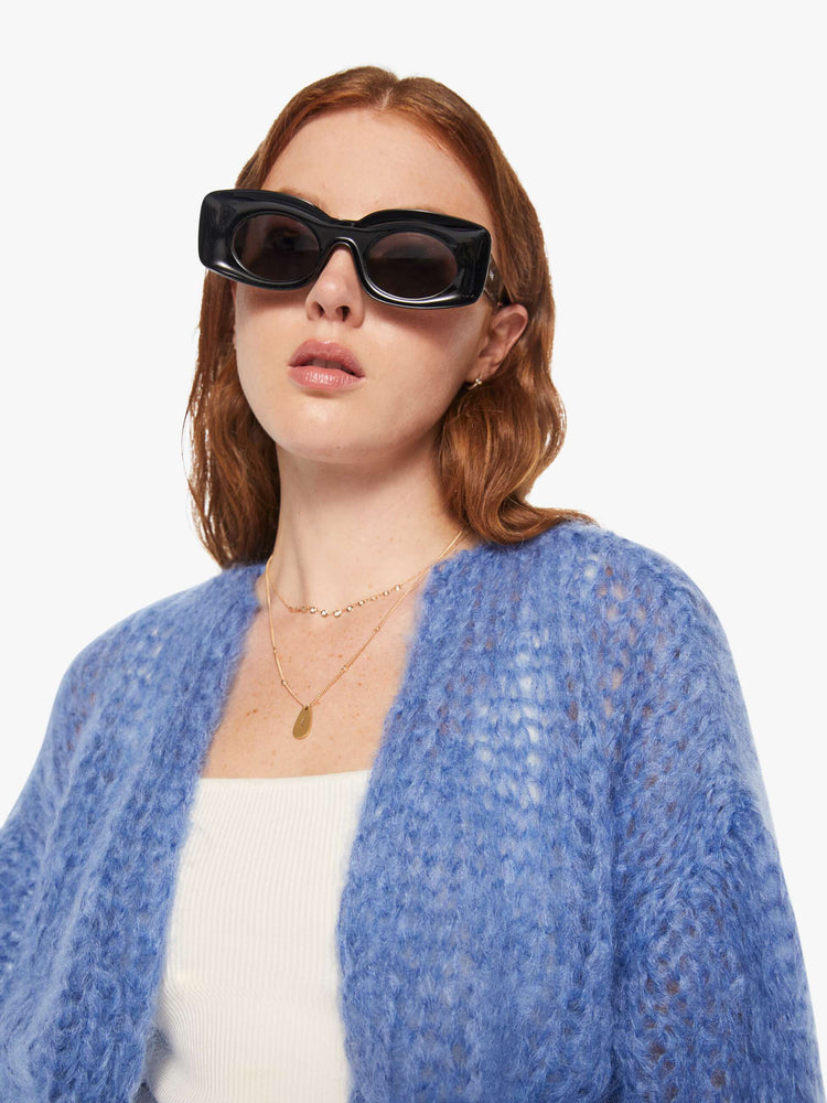 Close up view of a woman in a baby blue bomber jacket inspired cardigan.