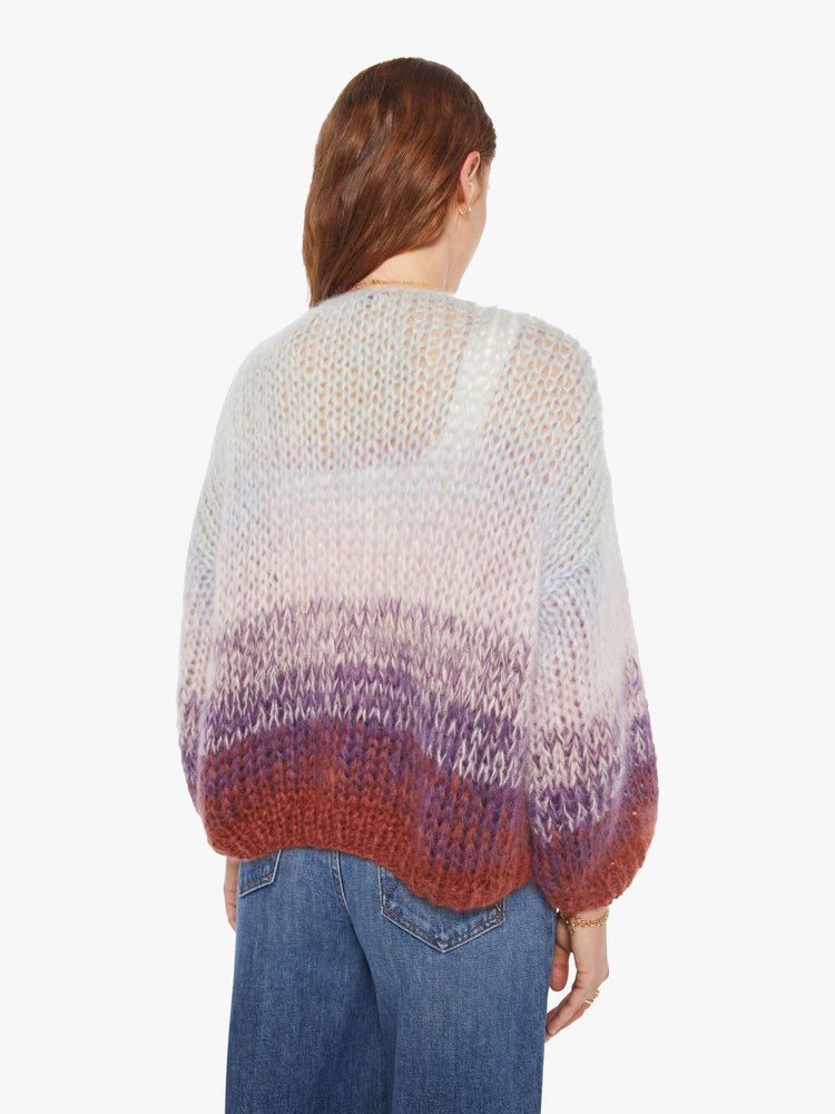 Back view of a woman in a  hand knit from a soft blend of mohair and wool in a light blue and purple gradient pattern with burgundy trim cardigan.