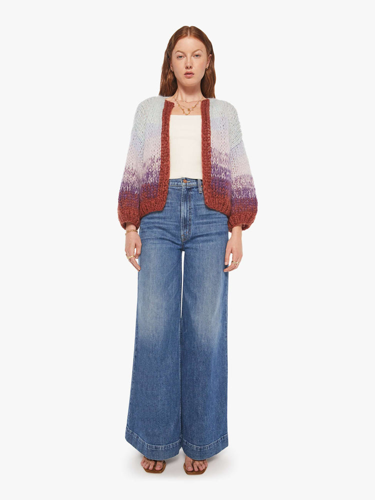 Full body view of a woman in a  hand knit from a soft blend of mohair and wool in a light blue and purple gradient pattern with burgundy trim cardigan.