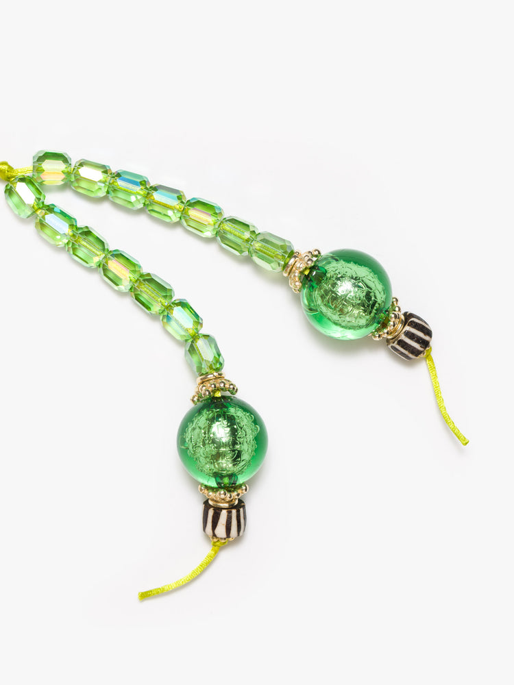 Close up view of a green keychain with a combination of glass, bone, acrylic and gold-plated beads.
